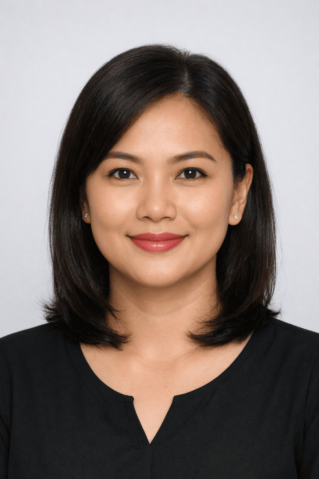Smiling Asian woman with shoulder-length dark hair wearing a black top against a gray background.